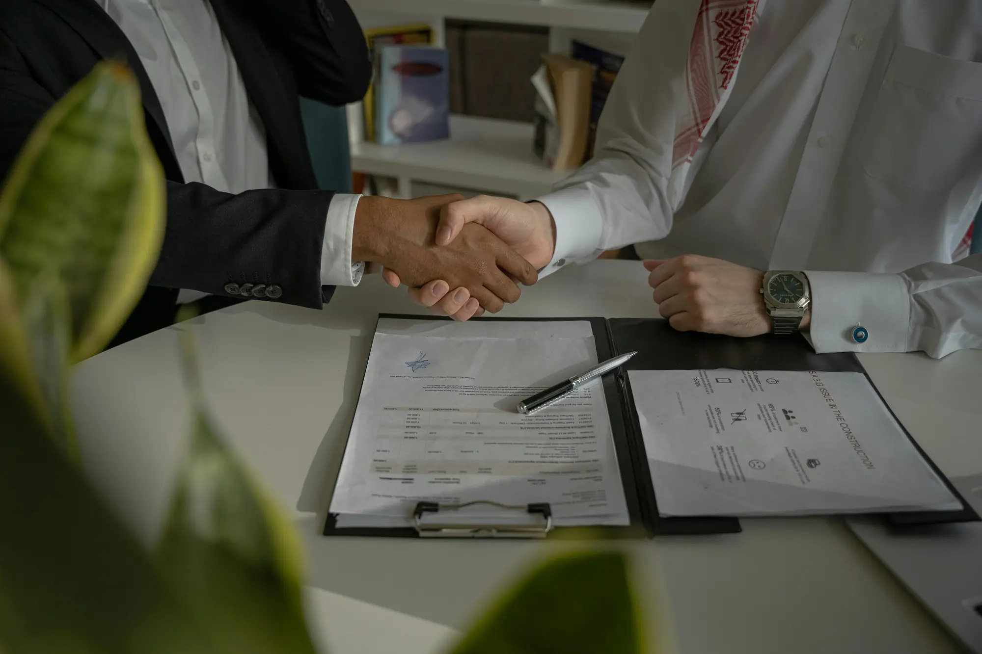 Two people shaking hands over signed papers